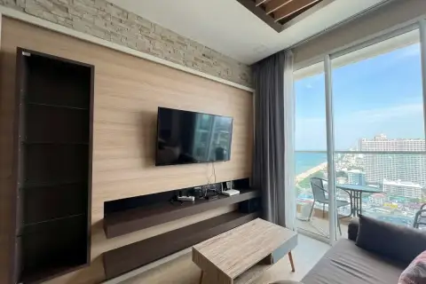 1 Bedroom Condo for Sale at Cetus Beachfront living room TV wall unit with balcony and panoramic Pattaya beach and city view