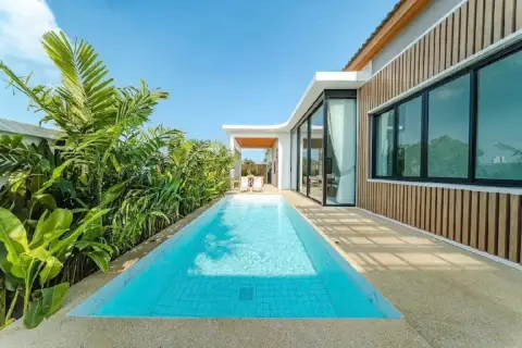 4 Bedroom House for Sale in Bang Lamung featuring a long, narrow swimming pool alongside the modern house exterior.