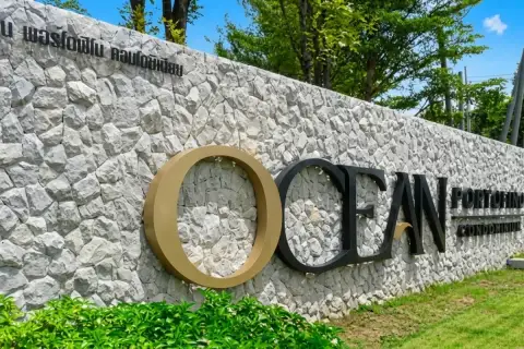 Ocean Portofino  stone entrance wall with gold and black branded signage surrounded by green trees