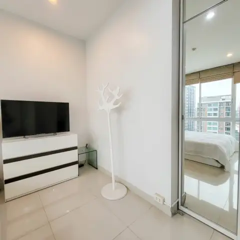 Studio Condo for Sale at Musselana dresser with TV and mirrored closet reflecting the bedroom