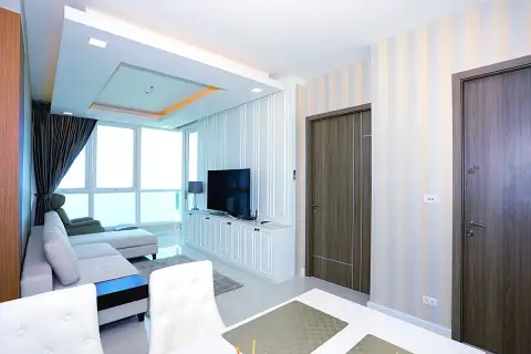 1 Bedroom Condo for Sale at Del Mare spacious living and dining area with striped wallpaper, TV unit, and sea-view balcony