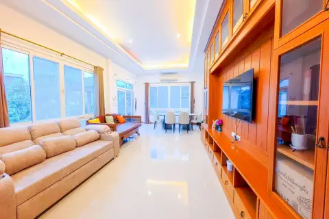 6 Bedroom House for Sale & Rent at Amorn Village, bright living area with sofas, dining table, and large windows.