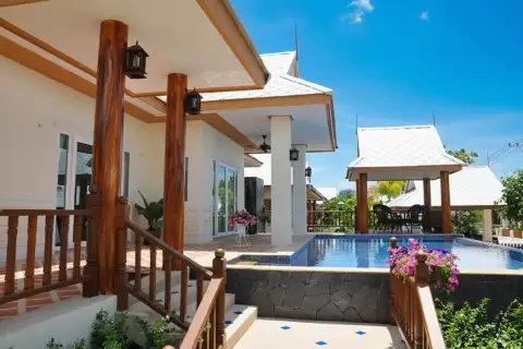 Amorn Village exterior with a swimming pool, wooden stairs, covered patio, and a traditional Thai style gazebo.