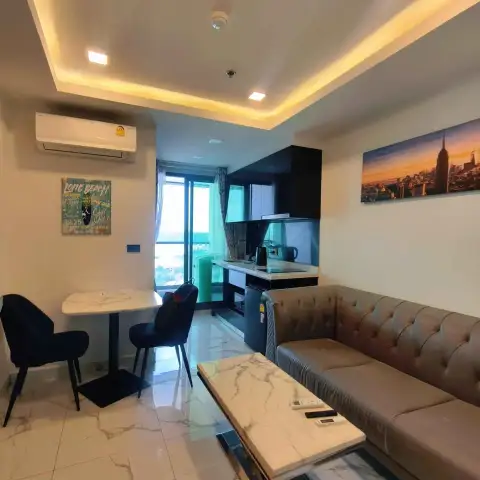 1 Bedroom Condo for Sale at Arcadia Millennium Tower living room with sofa, dining table, and kitchenette with city view balcony