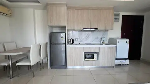 2 Bedroom Condo for Sale at Arcadia Beach Resort kitchen with wood cabinetry, fridge, and dining table