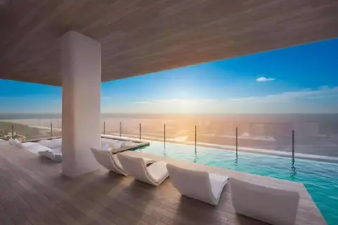 Arom Jomtien rooftop terrace with infinity pool, sun loungers, and ocean sunset view.