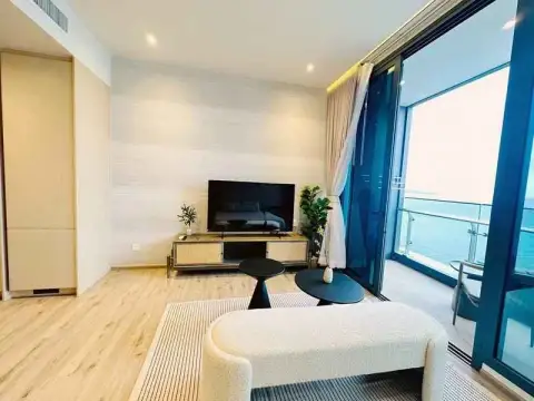1 Bedroom Condo for Rent at Arom Wongamat living area with TV unit and balcony access to sea view