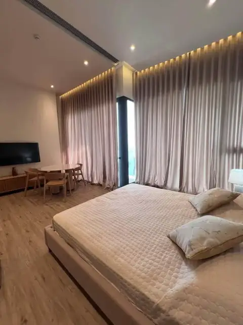 1 Bedroom Condo for Sale at Arom Wongamat bedroom with king bed, dining nook and curtained windows
