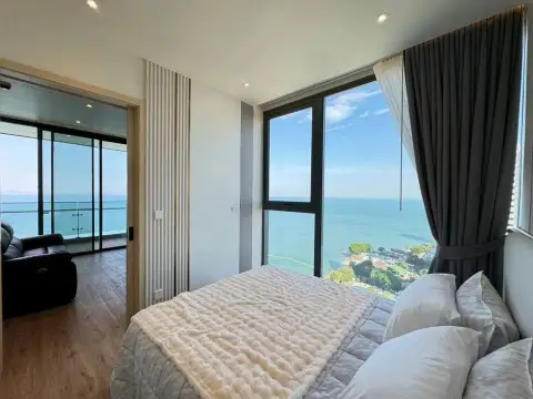 2 Bedroom Condo for Sale at Arom Wongamat bedroom with ocean view window and plush white bedding