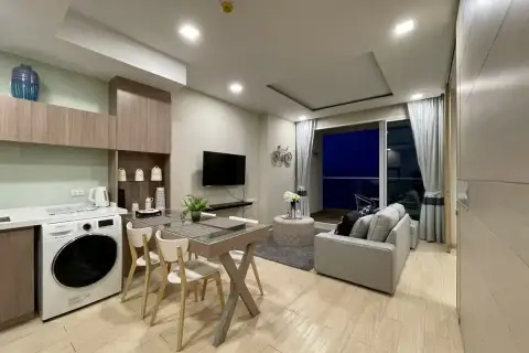 1 Bedroom Condo for Sale at Cetus Beachfront open-plan living area with dining table, washing machine, kitchen cabinets, and balcony