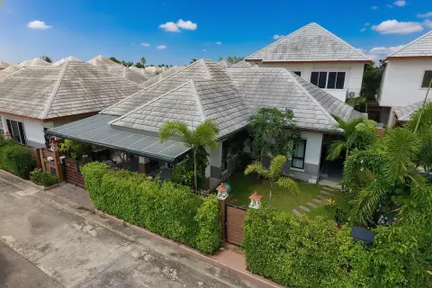 Baan Dusit Pattaya Park single-story house with a covered carport, small front yard, and a green hedge fence.