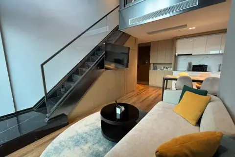 2 Bedroom Condo for Rent at Beverly Mountain Bay Pattaya double-height living space with staircase, TV and open kitchen view