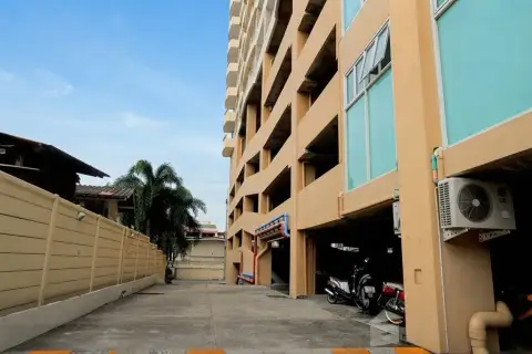 Sriracha Condo View ground-level parking area with motorbikes beside the condo tower