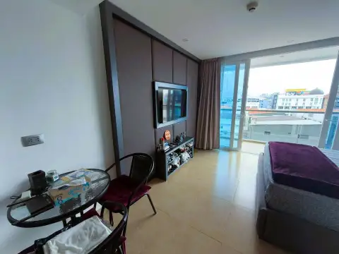 Studio Condo for Sale at Centara Avenue Residence and Suites living area with TV, dining table and balcony view