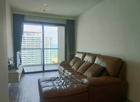 1 Bedroom Condo for Sale at Cetus Beachfront living room with brown sofa and large window overlooking sea and towers