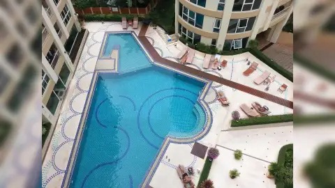 City Garden Pattaya outdoor swimming pool area with sun loungers, umbrellas, and curved apartment buildings.