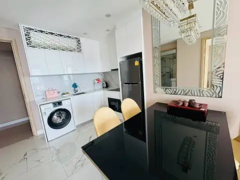 2 Bedroom Condo for Sale at Copacabana Beach Jomtien compact kitchen with washing machine, fridge, and dining table with mirror