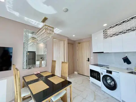 1 Bedroom Condo for Sale at Copacabana Beach Jomtien dining table with gold chairs and kitchenette with washing machine