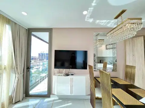 1 Bedroom Condo for Sale at Copacabana Beach Jomtien living area with wall-mounted TV, mirror, and balcony access