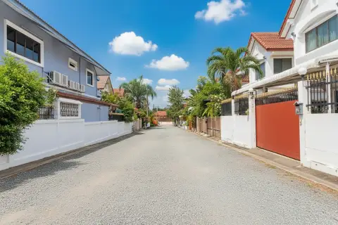 Country Club Villa street view with residential houses, lush hedges, and a clear sky.