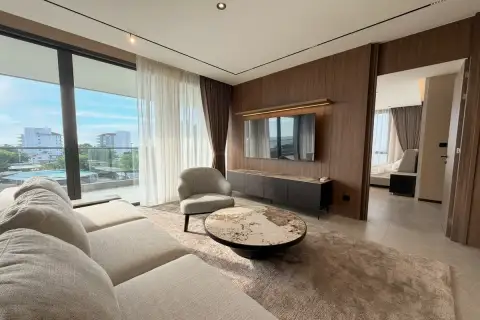 3 Bedroom Condo for Rent at Panora Estuaria bright living room with sectional sofa, round marble coffee table, wall-mounted TV and city view balcony