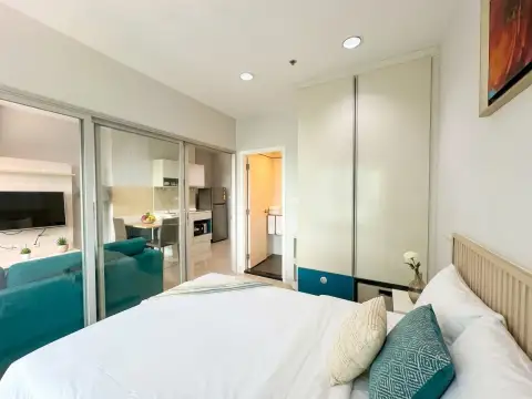 1 Bedroom Condo for Sale at Centric Sea bedroom with white bed, mirrored closet, and view into kitchen