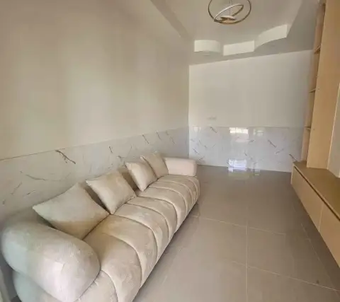 2 Bedroom Townhouse for Sale in East Pattaya living area with cream sofa, marble accent wall, and glossy tiled flooring