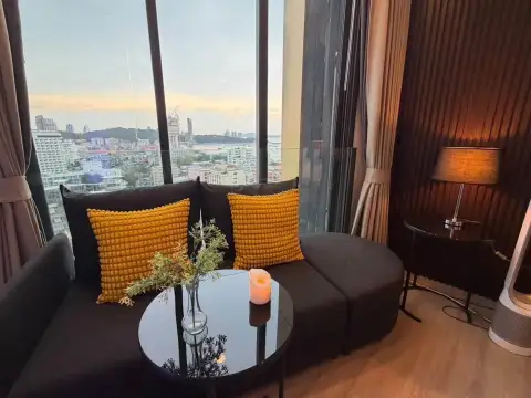 Studio Condo for Rent at EDGE Central Pattaya cozy lounge sofa facing floor-to-ceiling windows with sea view