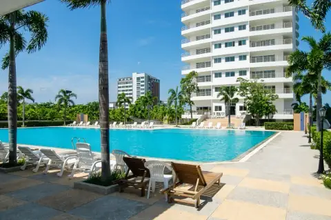View Talay 8 poolside deck with palm trees, sun loungers and condo building facade