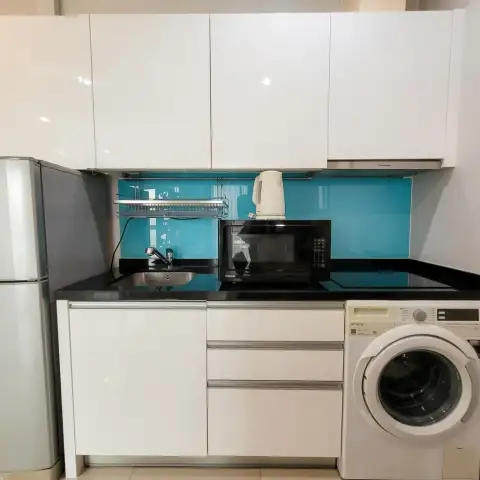 Studio Condo for Sale at Musselana kitchenette with black countertop, microwave, sink, and washing machine