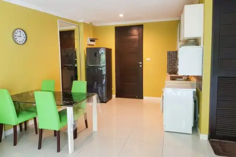 1 Bedroom Condo for Sale at Wongamat Privacy open-plan dining area with green chairs, black fridge, kitchen, and washing machine