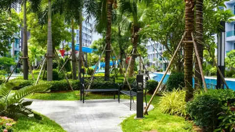 Dusit Grand Park 1 landscaped garden path with bench, palm trees and pool view