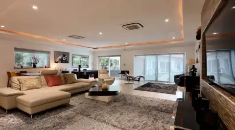 6 Bedroom House for Rent in Jomtien outdoor swimming pool with sun loungers, palm trees, and artificial turf garden
