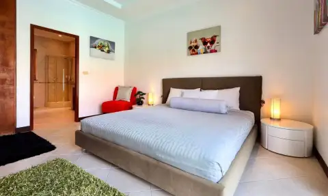 6 Bedroom House for Rent in Jomtien bedroom with king-size bed, red accent chair, and en-suite bathroom
