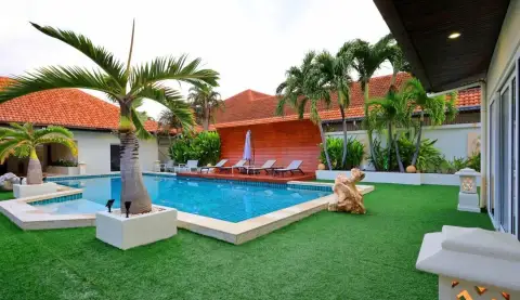 6 Bedroom House for Rent in Jomtien exterior view of villa with tiled roof, pool deck, and landscaped lawn