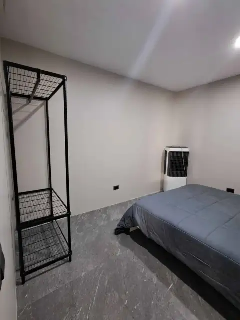 2 Bedroom Condo for Sale at Jomtien Beach Condominium second bedroom with bed and black wire shelving unit