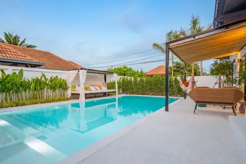Srisuk Villa private swimming pool with outdoor daybed, lush green plants, and a shaded seating area.