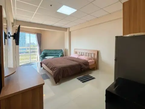 2 Bedroom Condo for Sale at Jomtien Beach Condominium bedroom corner with bed, sofa, and window overlooking the city