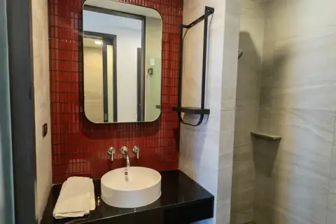 1 Bedroom Condo for Rent at EDGE Central Pattaya bathroom with round vessel sink, red mosaic tiles, mirror, and walk-in shower