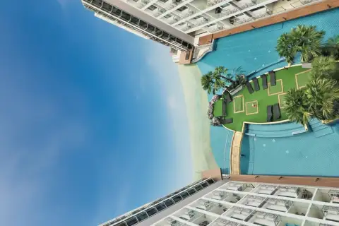 Laguna Beach Resort 1 overhead view of the lagoon pool, artificial beach, and sun loungers on a green island.