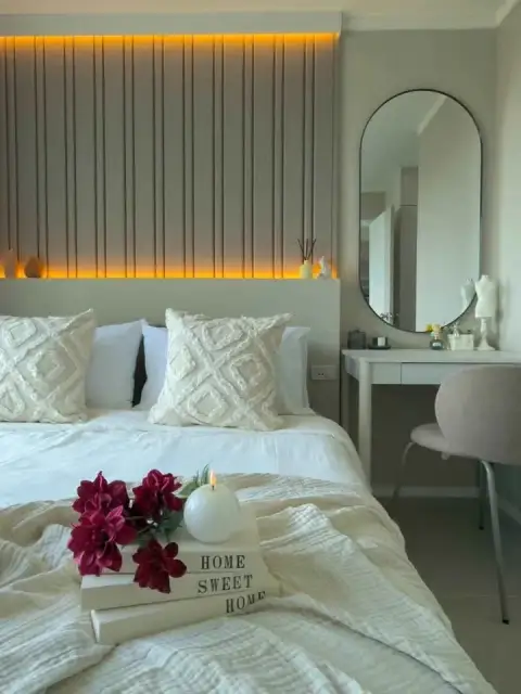 1 Bedroom Condo for Sale at Lumpini Ville Naklua-Wongamat bedroom with white bedding, slatted accent wall and round mirror vanity