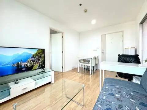 1 Bedroom Condo for Sale at Lumpini Ville Naklua-Wongamat open living area with flat-screen TV and glass coffee table