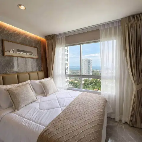 1 Bedroom Condo for Sale at Lumpini Ville Naklua-Wongamat bedroom with king bed and large window overlooking sea and city