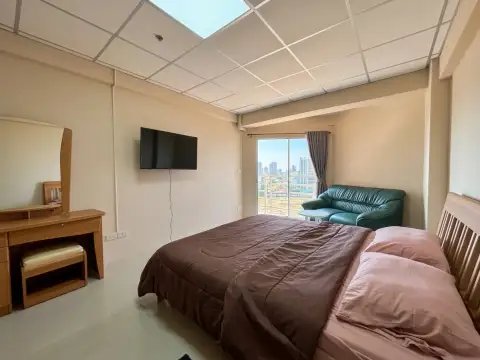 2 Bedroom Condo for Sale at Jomtien Beach Condominium bedroom with green sofa, wall-mounted TV, and balcony city view