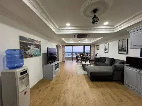 1 Bedroom Condo for Sale at Metro Jomtien Condotel living room with sectional sofa, TV and sea-view balcony