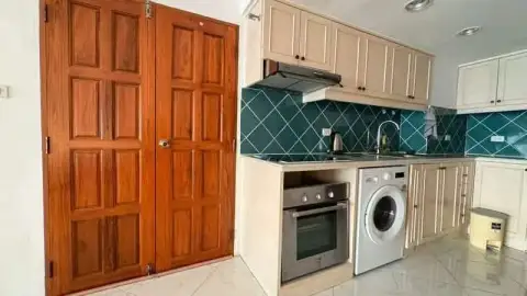 Studio Condo for Sale at Metro Jomtien Condotel kitchen with wooden cabinets, oven, and washing machine