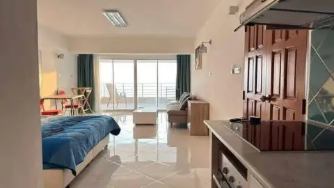 Studio Condo for Sale at Metro Jomtien Condotel open-plan living area with bed, sofa, and balcony access
