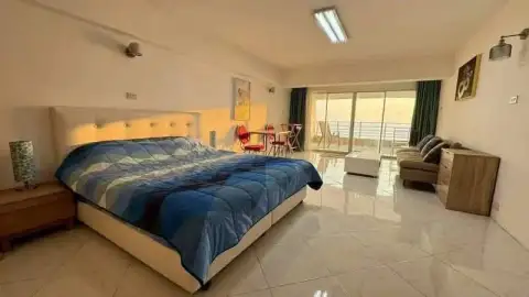 Studio Condo for Sale at Metro Jomtien Condotel bedroom with king bed, sofa, and sea-view balcony