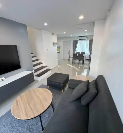 3 Bedroom House for Rent in Na Kluea open-plan living room with sofa, staircase, and dining area