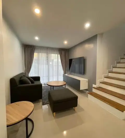 3 Bedroom House for Rent in Na Kluea living room with gray sofa, TV console, and staircase